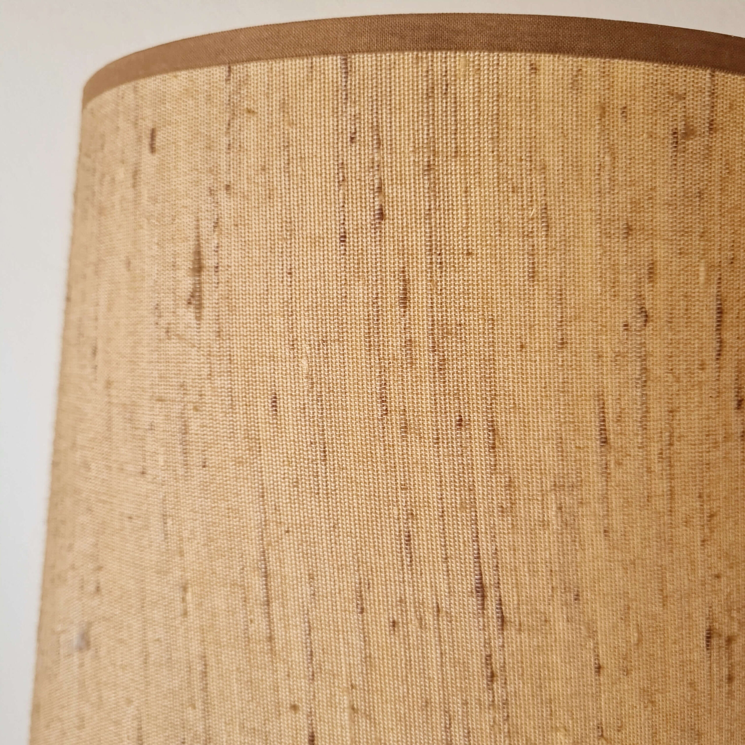 Gros plan sur l'abat-jour en tissu lin texturé de la lampe vintage, détail de la bordure.