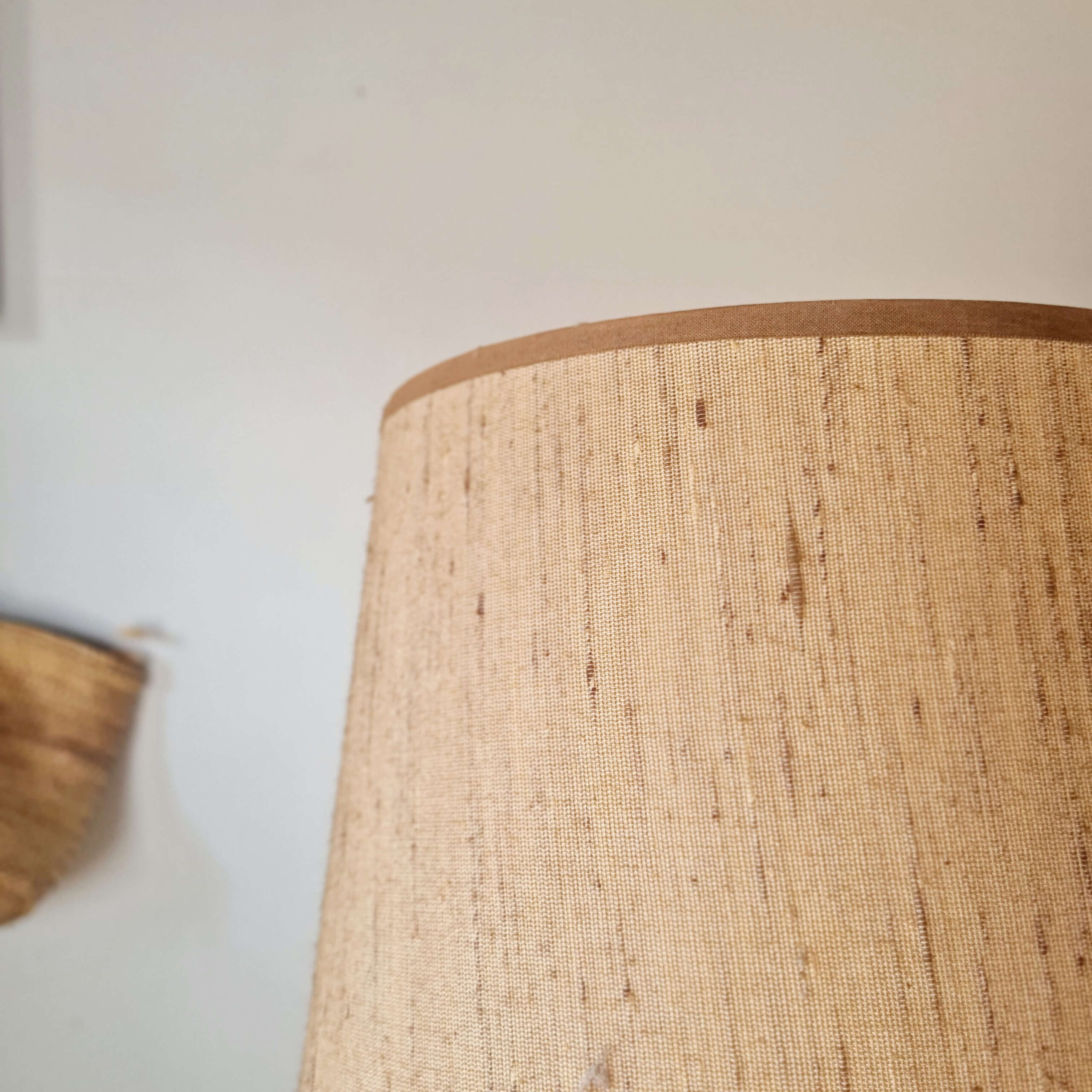 Vue rapprochée de la texture tissée de l'abat-jour beige de la lampe en céramique.