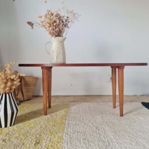 Table basse scandinave au plateau ovale sur pieds effilés.