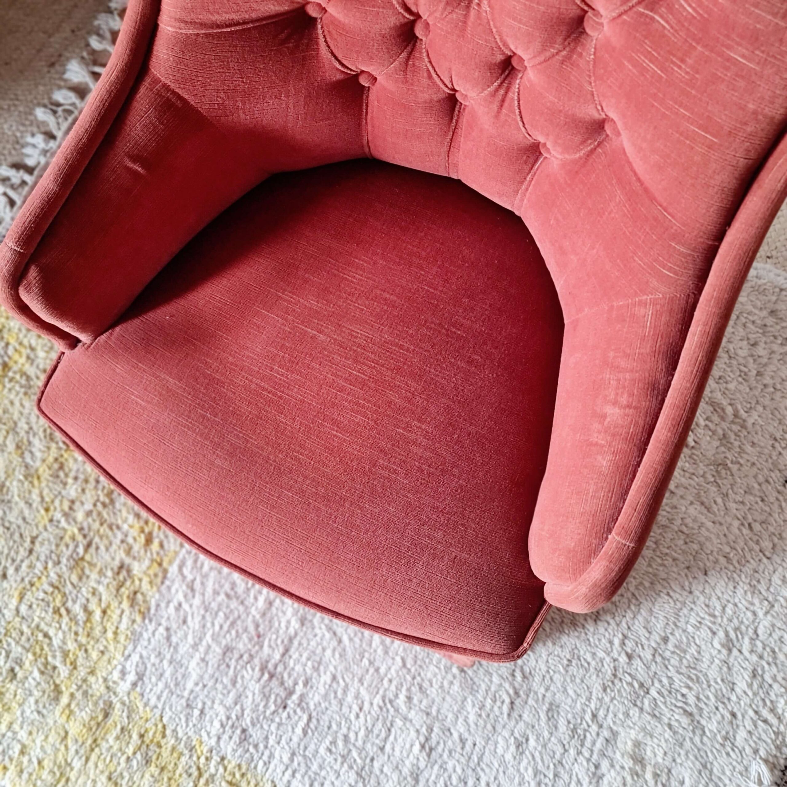 Vue en plongée sur l'épaisse assise en tissu texturé d'un fauteuil crapaud ancien.