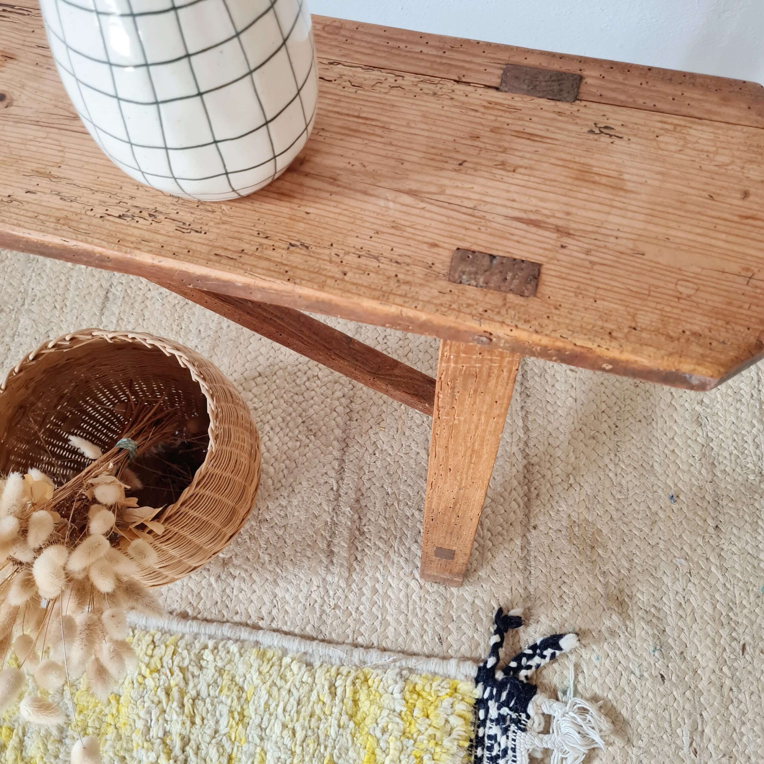 Gros plan sur l'assise en bois vieilli d'un banc ancien, montrant des assemblages traditionnels et des traces d'usure authentiques