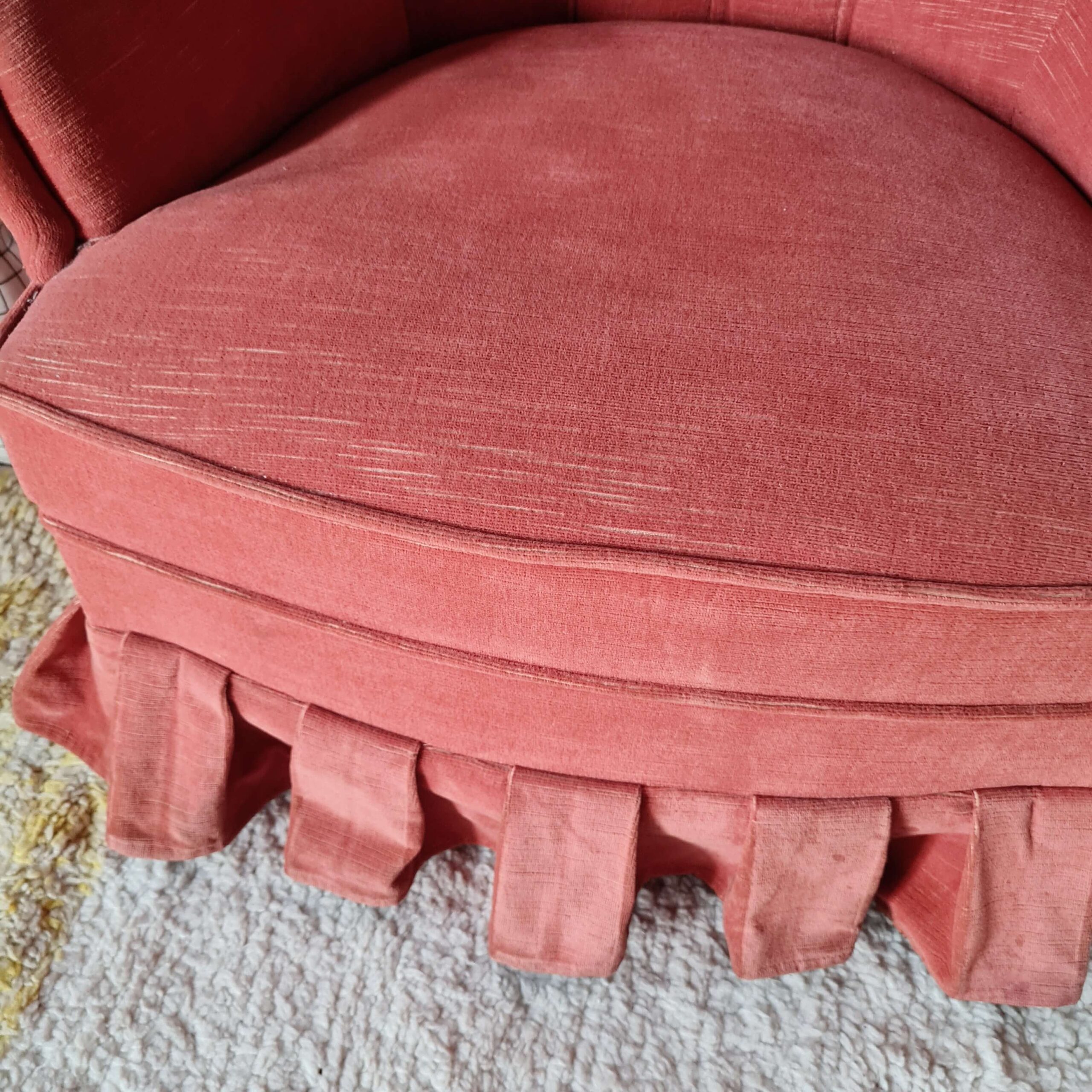 Vue en plongée sur l'épaisse assise et les finitions passepoilées d'un fauteuil crapaud rétro en tissu.