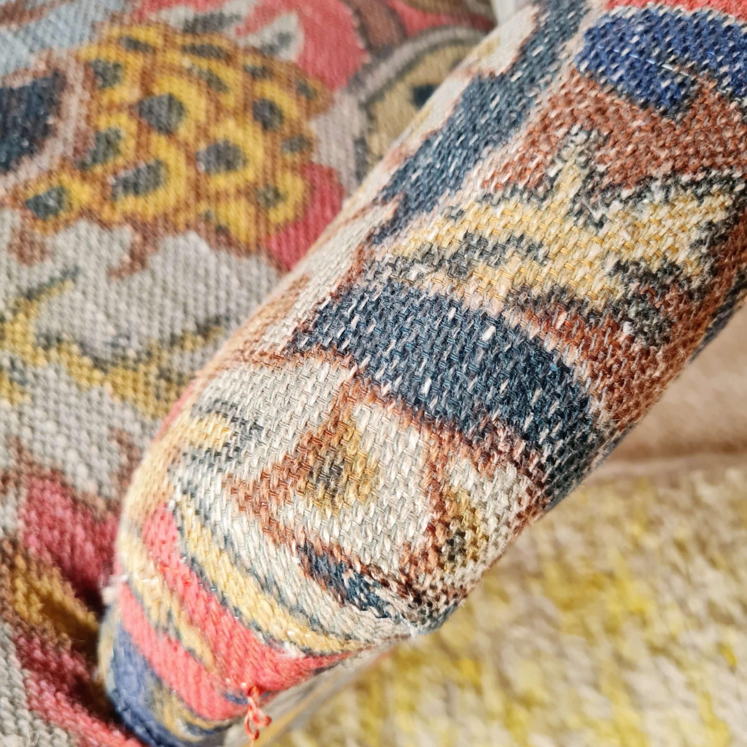 Gros plan sur le tissage texturé et les motifs colorés d'un fauteuil crapaud vintage au charme rétro.