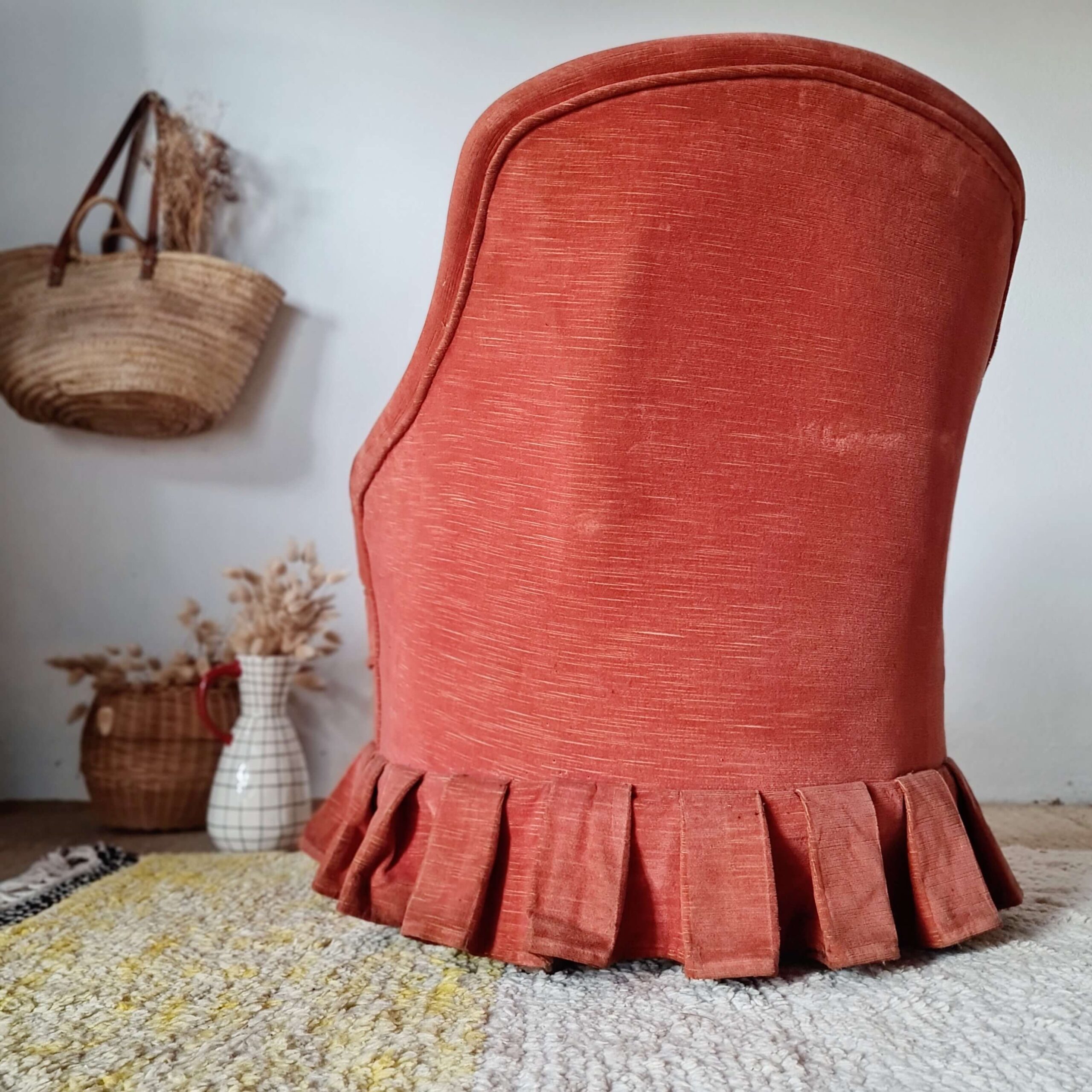 Vue arrière d'un fauteuil de salon ancien recouvert d'un tissu rouge texturé.