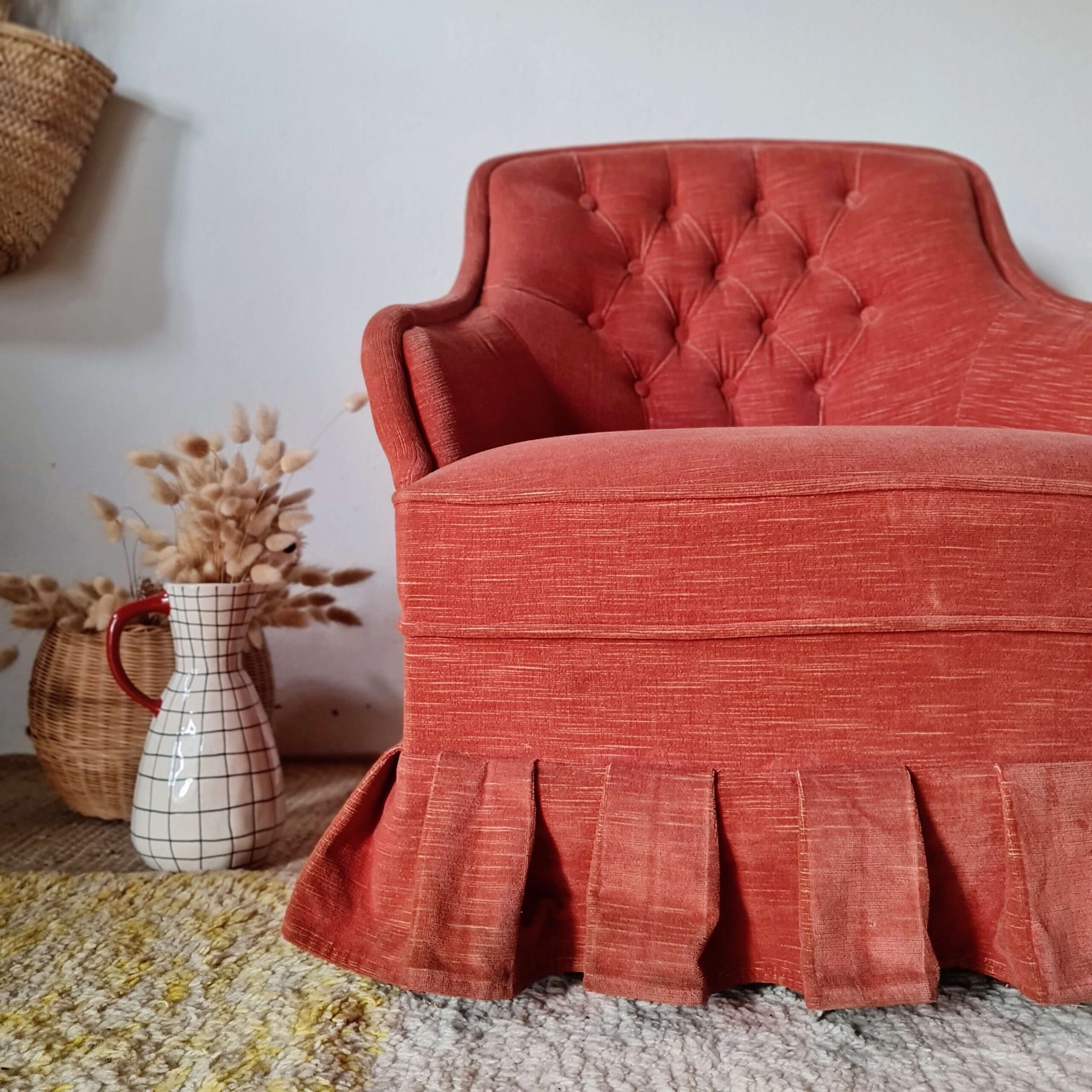 Vue rapprochée d'un fauteuil crapaud rétro capitonné, mettant en avant son assise confortable et sa jupe à plis creux.