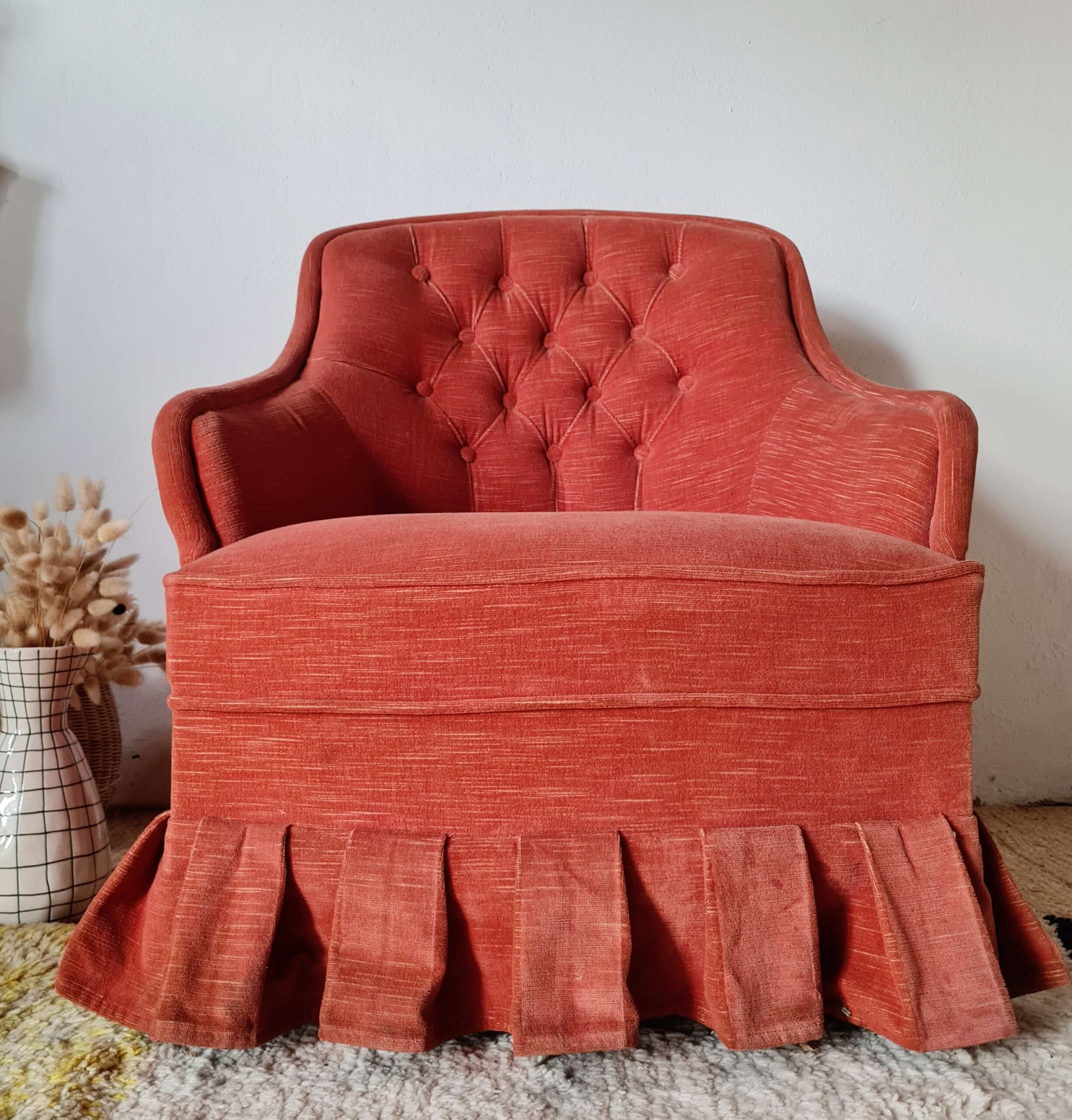 Vue de face d'un fauteuil crapaud vintage au dossier capitonné et au revêtement en tissu texturé couleur rouge terracotta