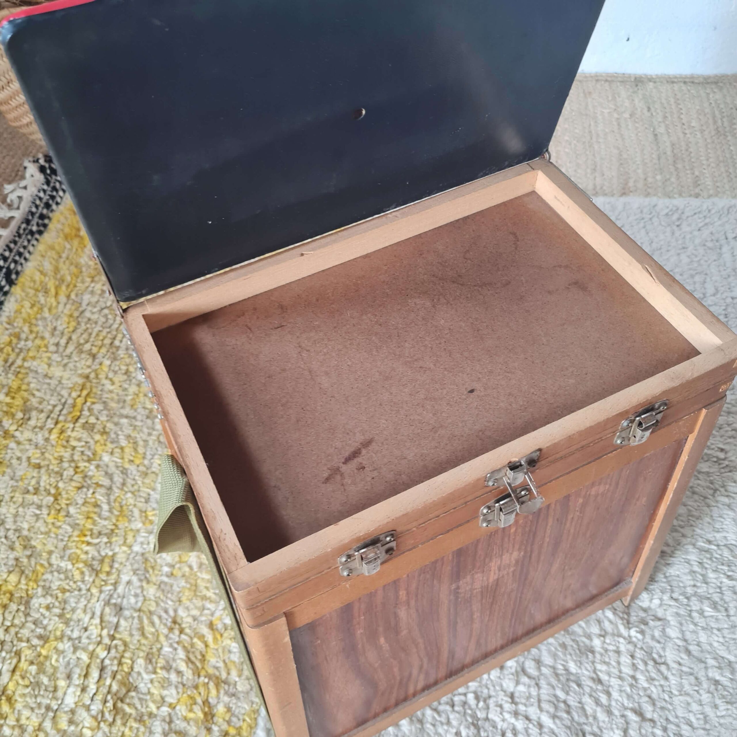 Vue plongeante sur l'intérieur ouvert du tabouret de pêcheur, révélant le compartiment de rangement principal et le dessous de l'assise.