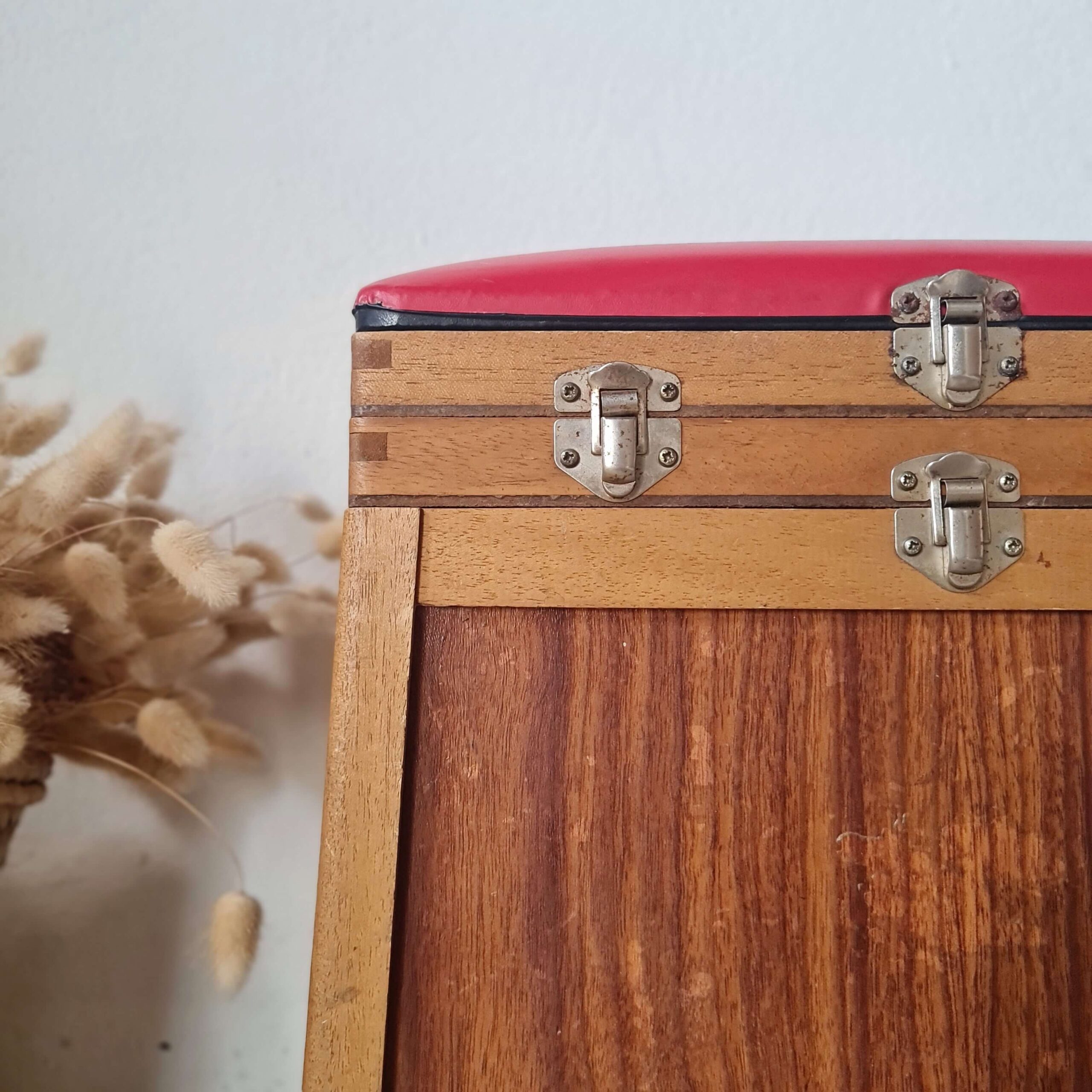 Focus sur le loquet et la charnière métalliques fixés sur le bois du tabouret de pêcheur. La quincaillerie est d'origine, légèrement oxydée par le temps.