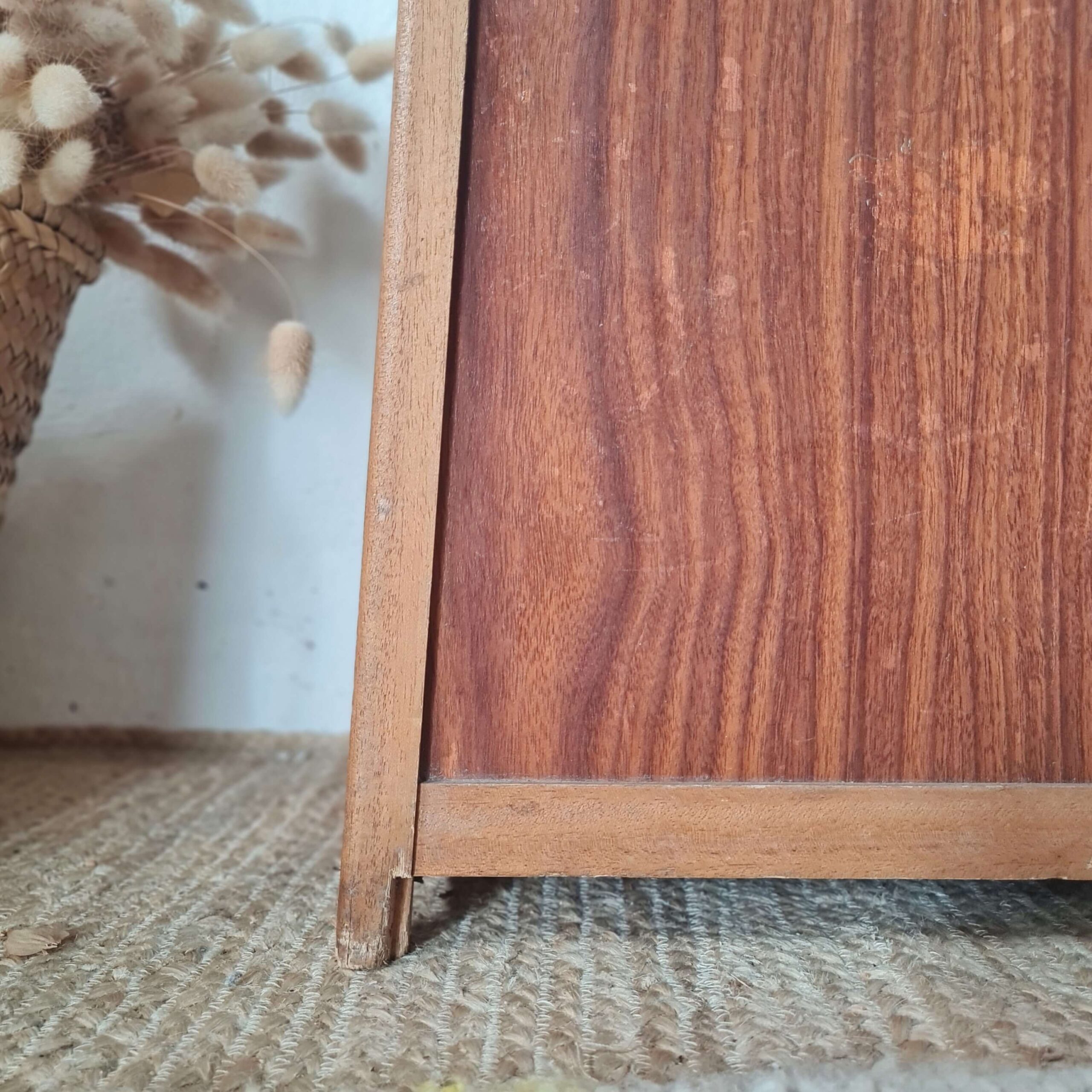 Vue en très gros plan montrant l'assemblage et la patine du pied en bois de l'ancien tabouret de pêcheur. Le bois montre des signes d'usure légère et de vécu.