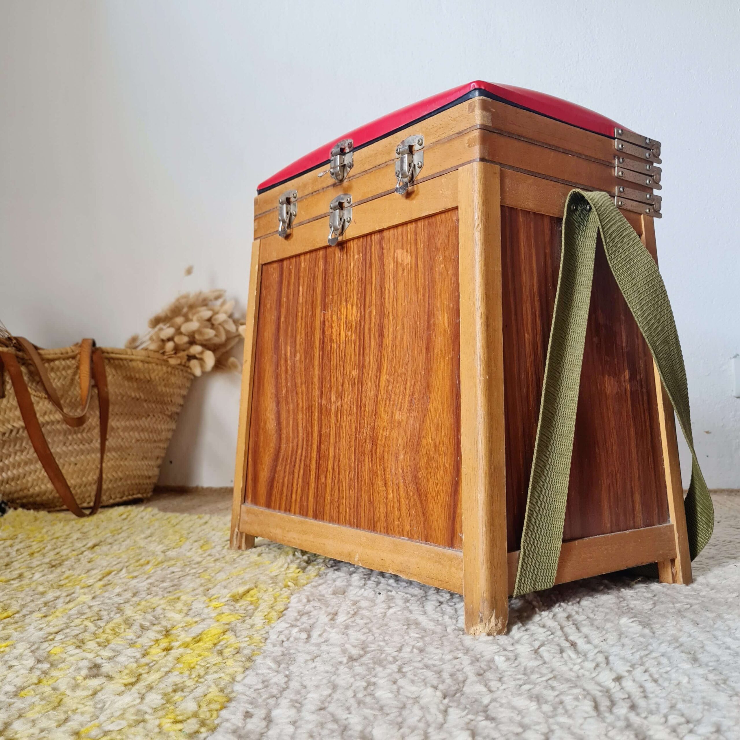 Vue de profil du tabouret de pêcheur en bois équipé de sa sangle de transport en tissu vert kaki.
