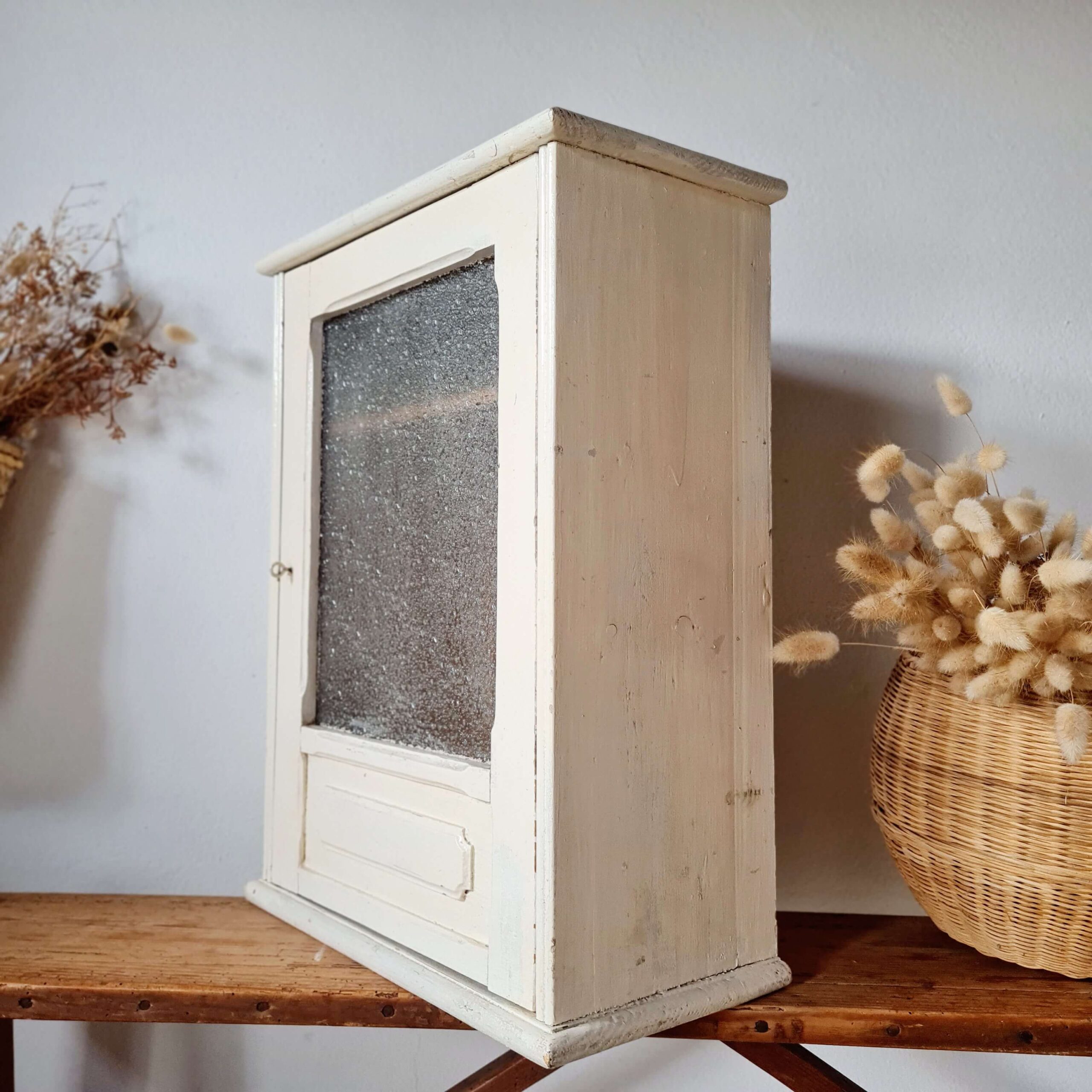 Vue de profil gauche de la petite armoire suspendue vintage, mettant en valeur la profondeur du meuble et son cadre peint en blanc patiné.