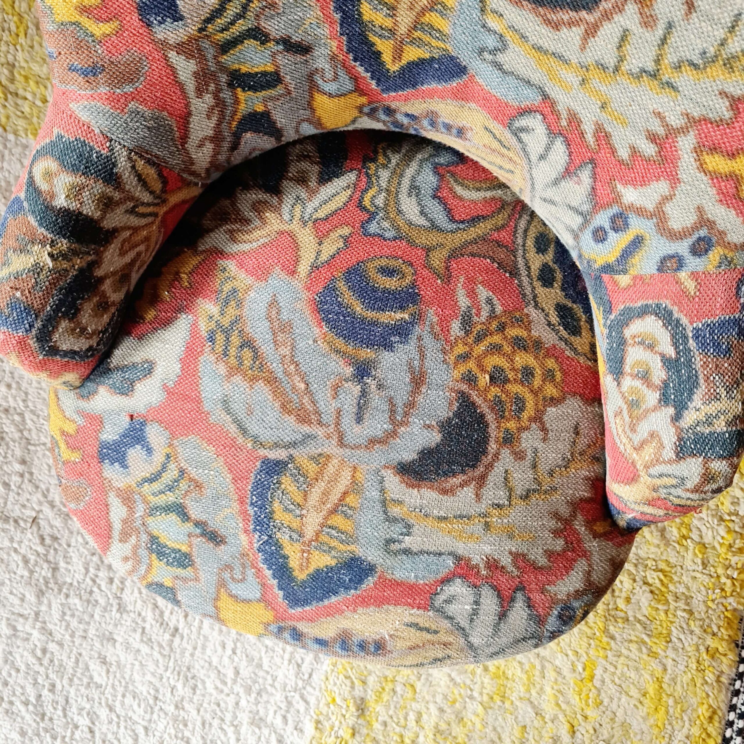 Vue du dessus de l'assise confortable d'un fauteuil crapaud vintage habillé d'un tissu fleuri ethnique