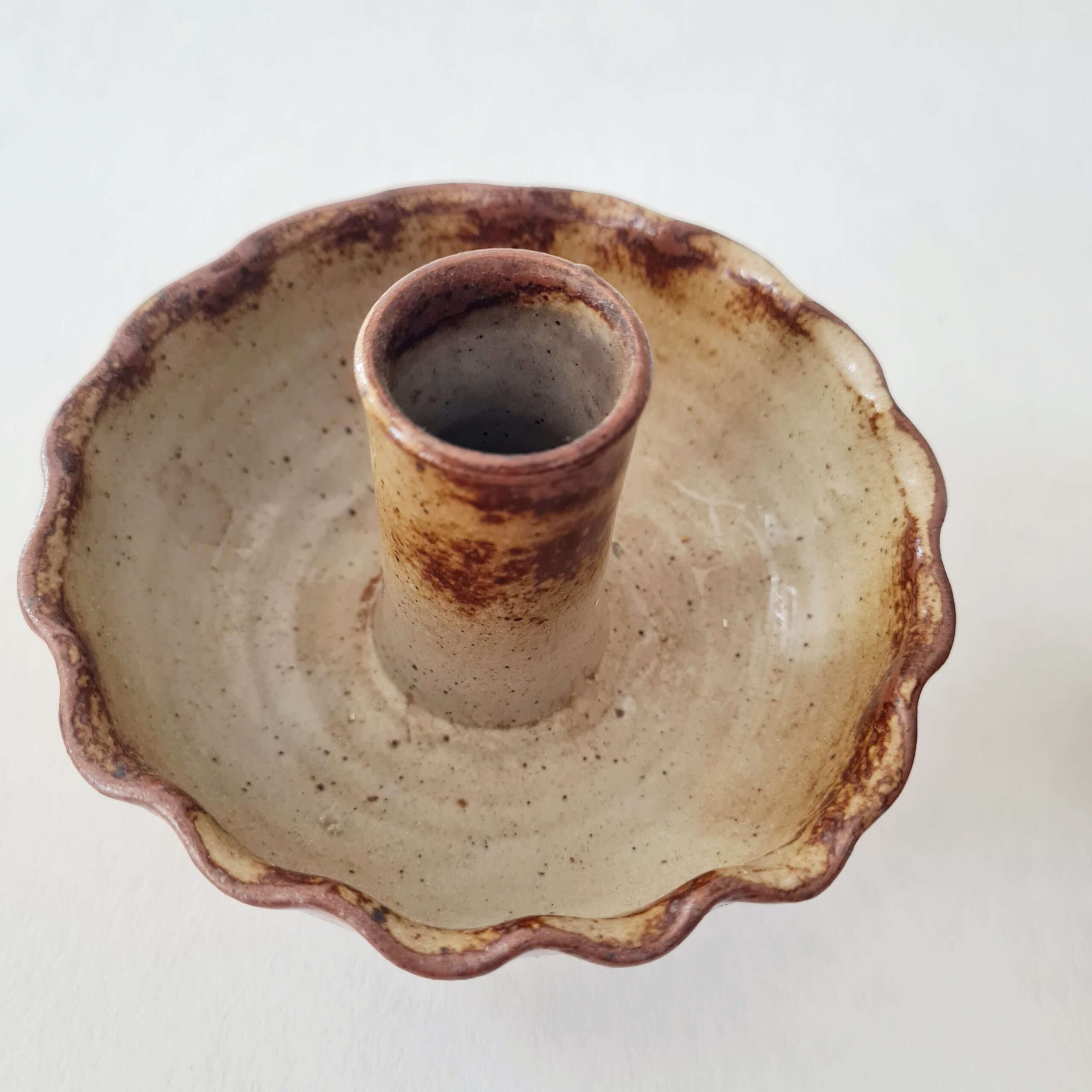 Focus sur un bougeoir en grès émaillé beige moucheté avec col marron effilé.