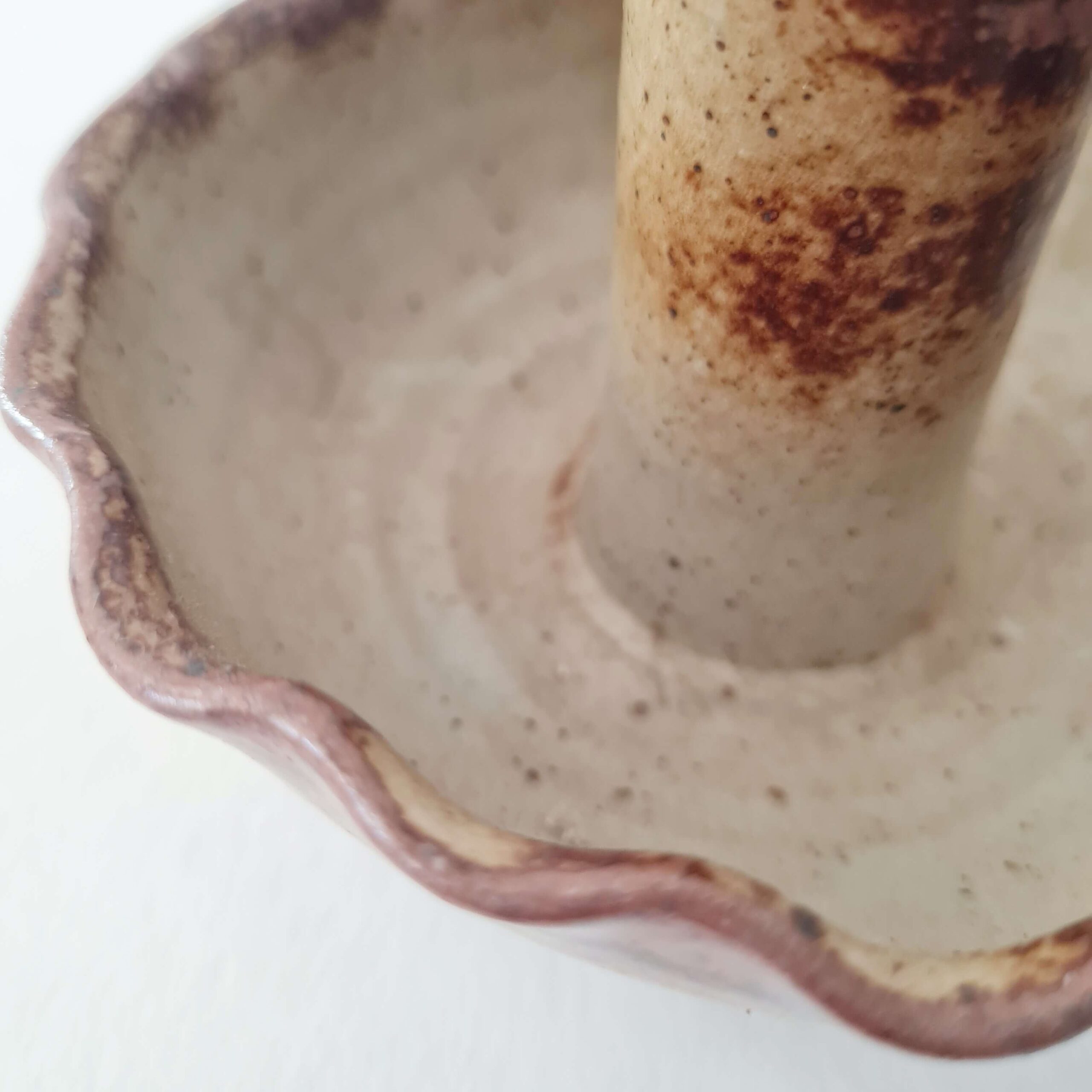 Vue de trois quarts d'un bougeoir en grès pyrité artisanal à bords ondulés.