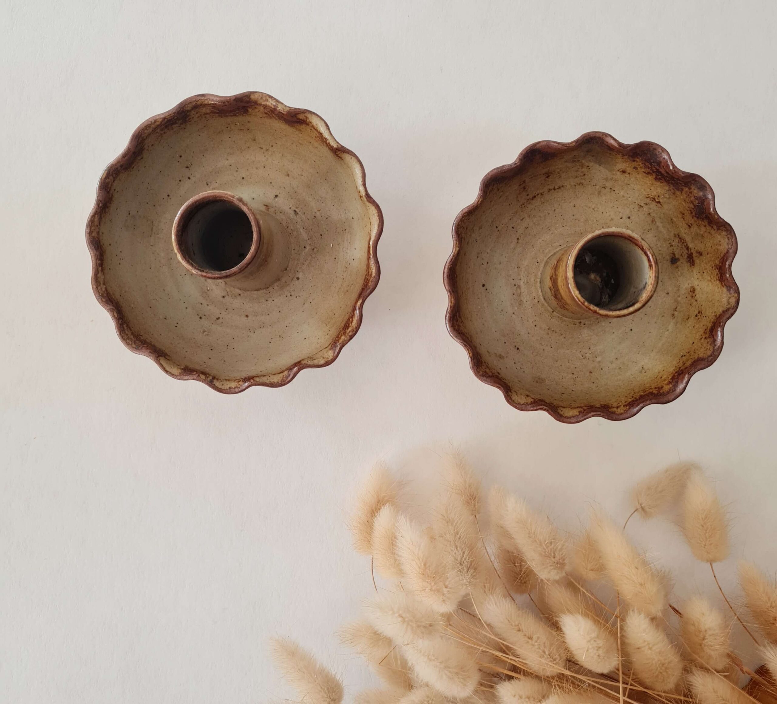 Vue plongeante de deux bougeoirs artisanaux en grès pyrité aux bords festonnés brun roussâtre