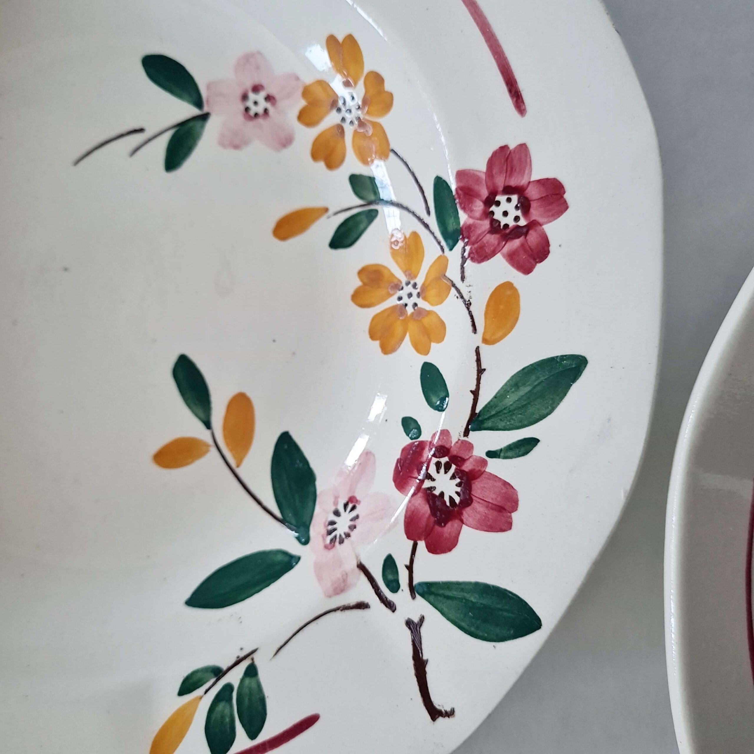 Détail de la guirlande florale peinte à la main sur assiette en faïence ancienne