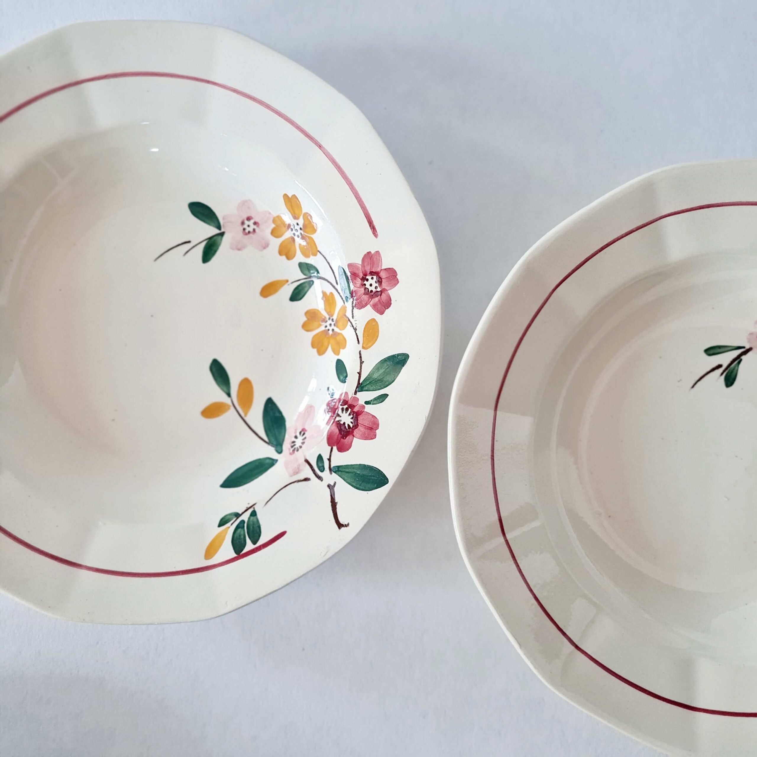 Deux assiettes creuses en faïence blanche à marli octogonal et liseré bordeaux