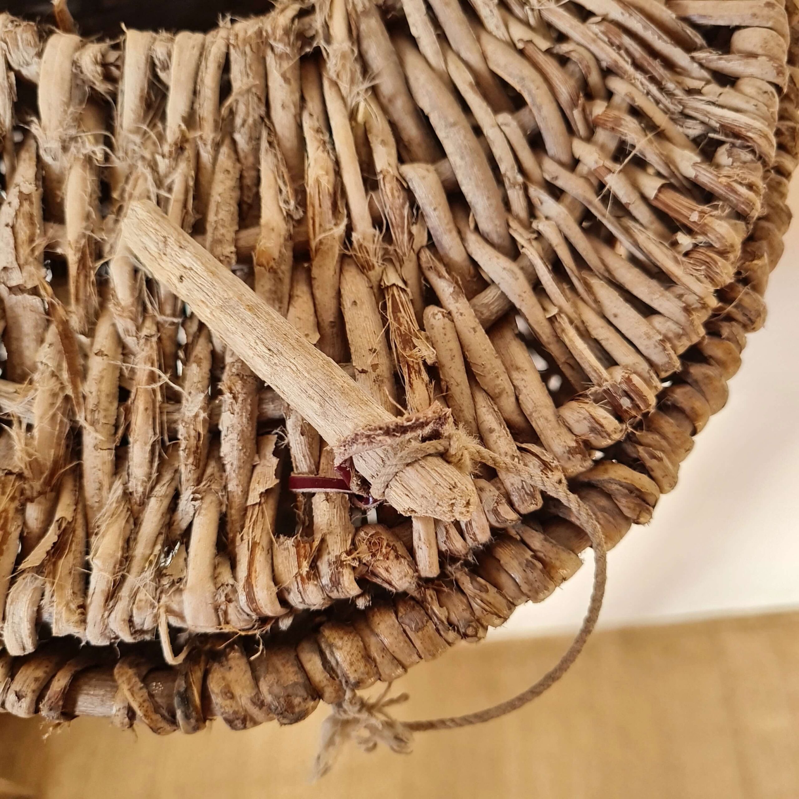 Gros plan sur la cheville en bois d'origine servant de fermoir au panier tressé.