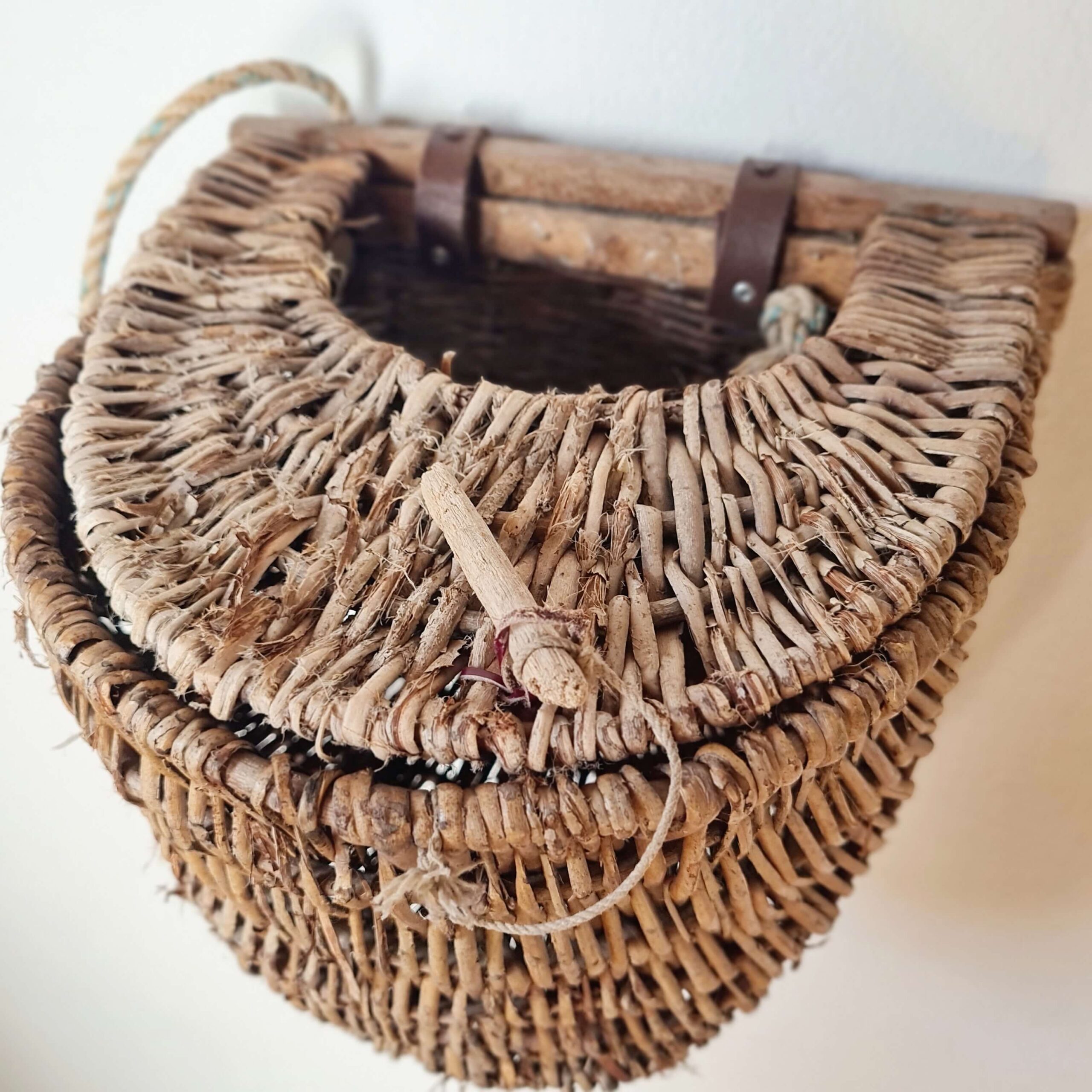 Détail du couvercle demi-lune et du fermoir en bois d'un panier ancien en osier.