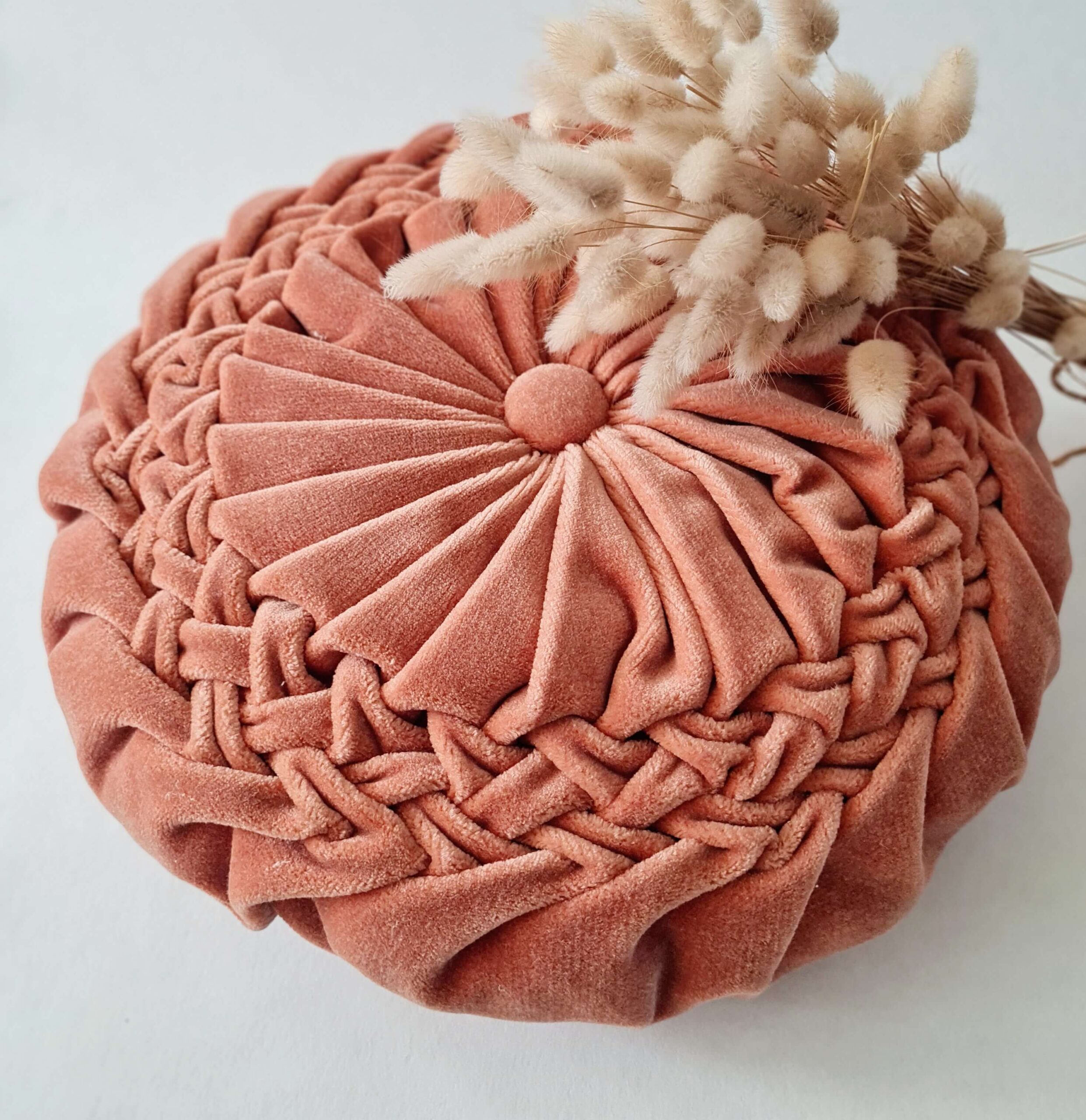 Coussin rond rétro en velours vieux rose poudré présenté avec fleurs séchées